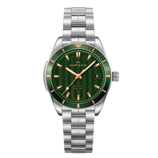 Front view of the Norqain Independence Green Dial Watch featuring a textured green dial, matching green bezel, rose gold-tone hour markers, date window and stainless steel bracelet.