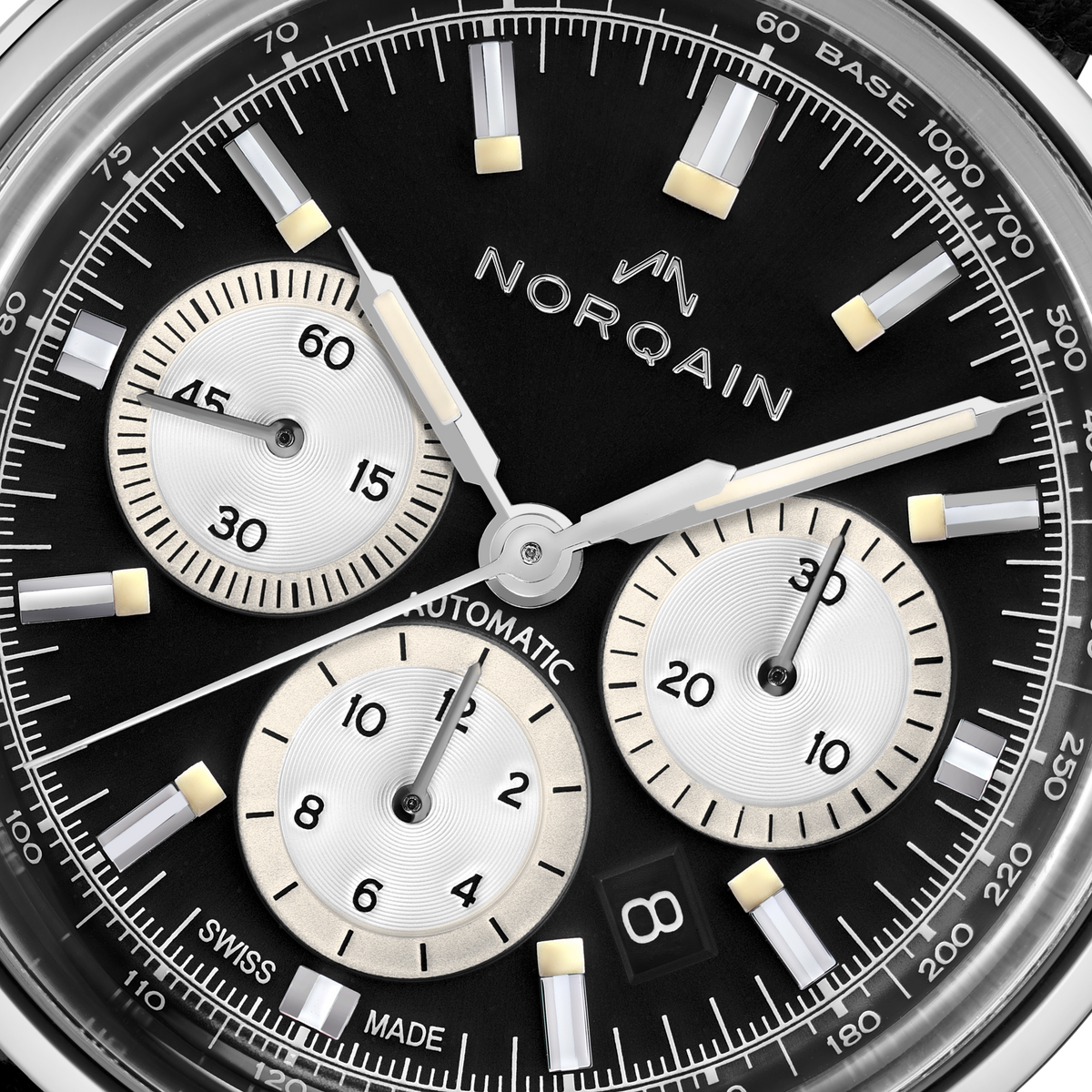 Close-up detail of the Norqain Freedom 60 Chronograph with black dial, silver panda-style sub-dials, luminous hands and markers, date window and Swiss automatic chronograph movement.