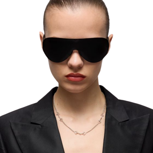 Model wearing the Gucci Staffa sterling silver necklace with a black blazer and oversized shield sunglasses, highlighting the necklace's delicate stirrup-inspired design.