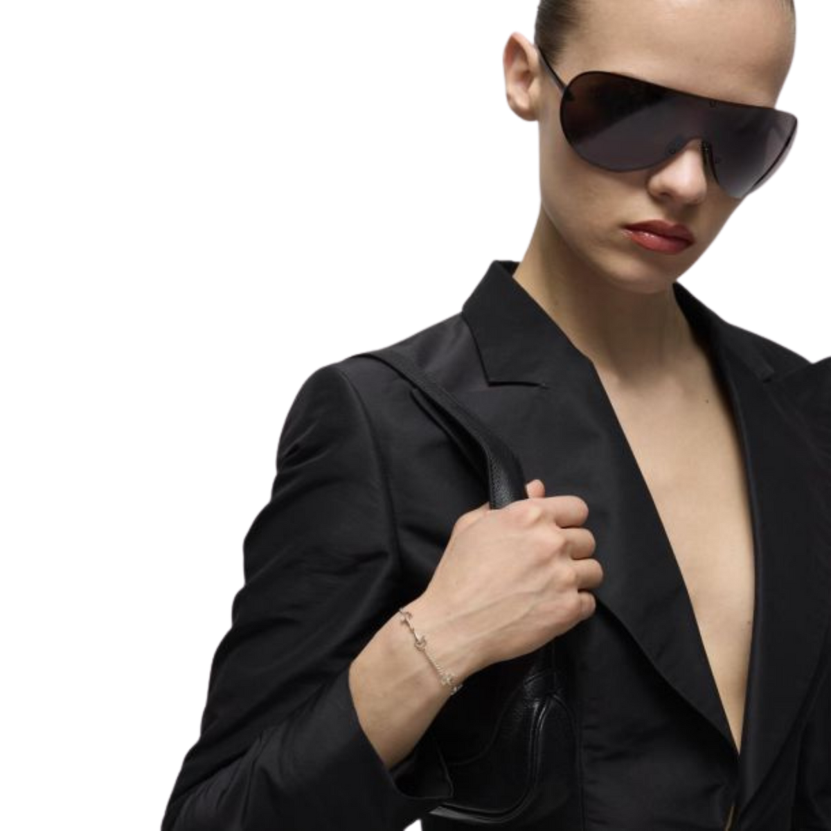 Model wearing the Gucci Staffa sterling silver bracelet with a black blazer and oversized shield sunglasses, showcasing the bracelet's delicate stirrup-inspired design.