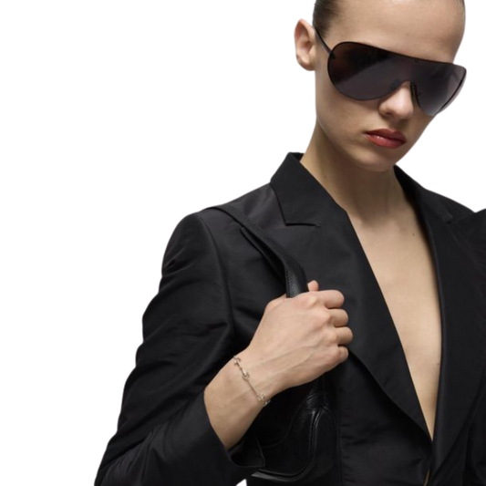 Model wearing the Gucci Staffa sterling silver bracelet with a black blazer and oversized shield sunglasses, showcasing the bracelet's delicate stirrup-inspired design.